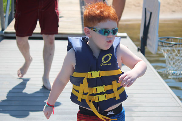 Cash with his life jacket on struts down the deck to swim in the lake at Heathers Camp.