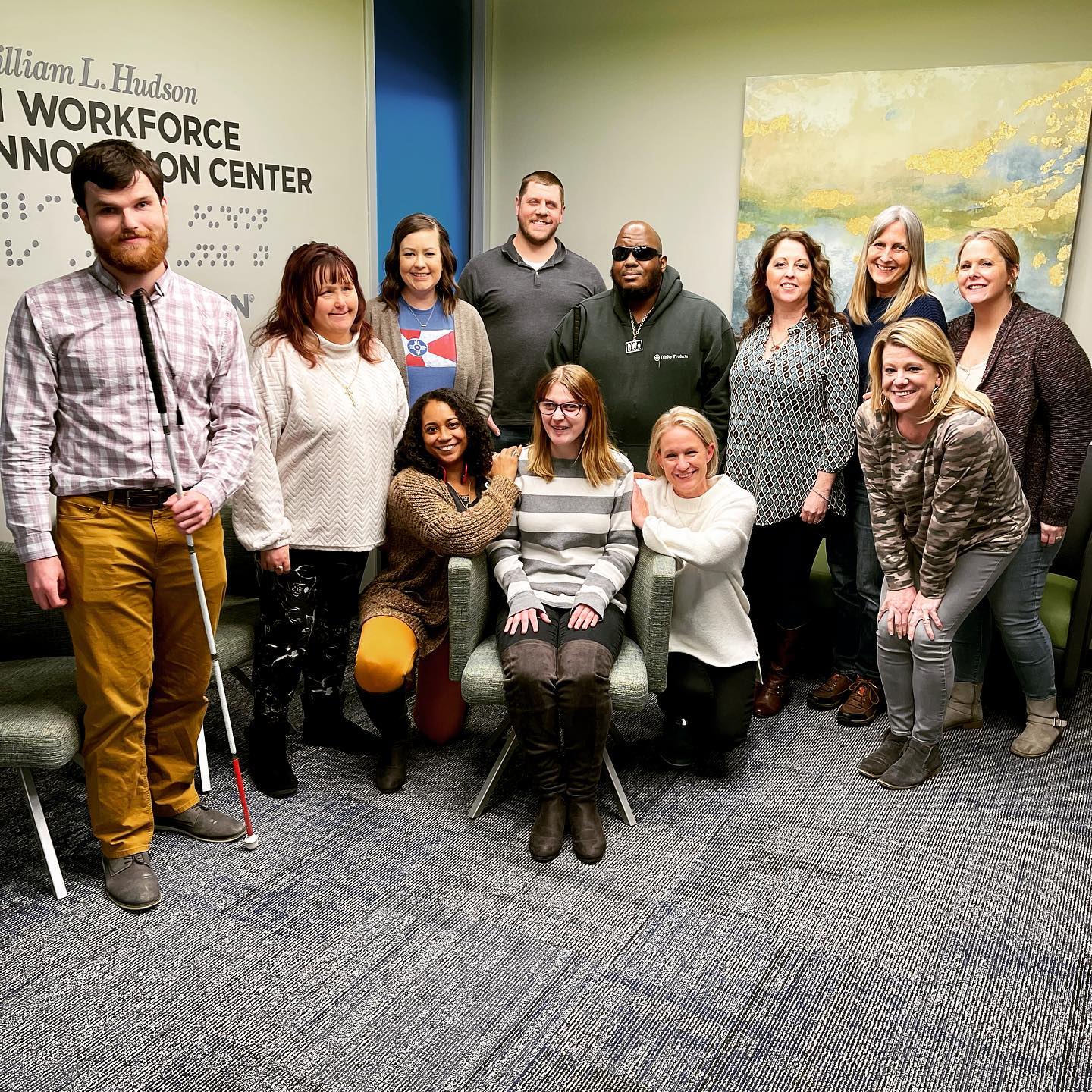 Alison sitting with a big group of people at Envision's Workforce Innovation Center during a goodbye party for her