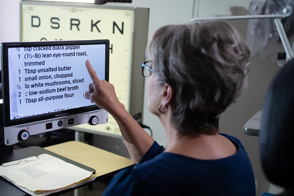 Woman touching a screen that enlarges text from a paper or book, etc.