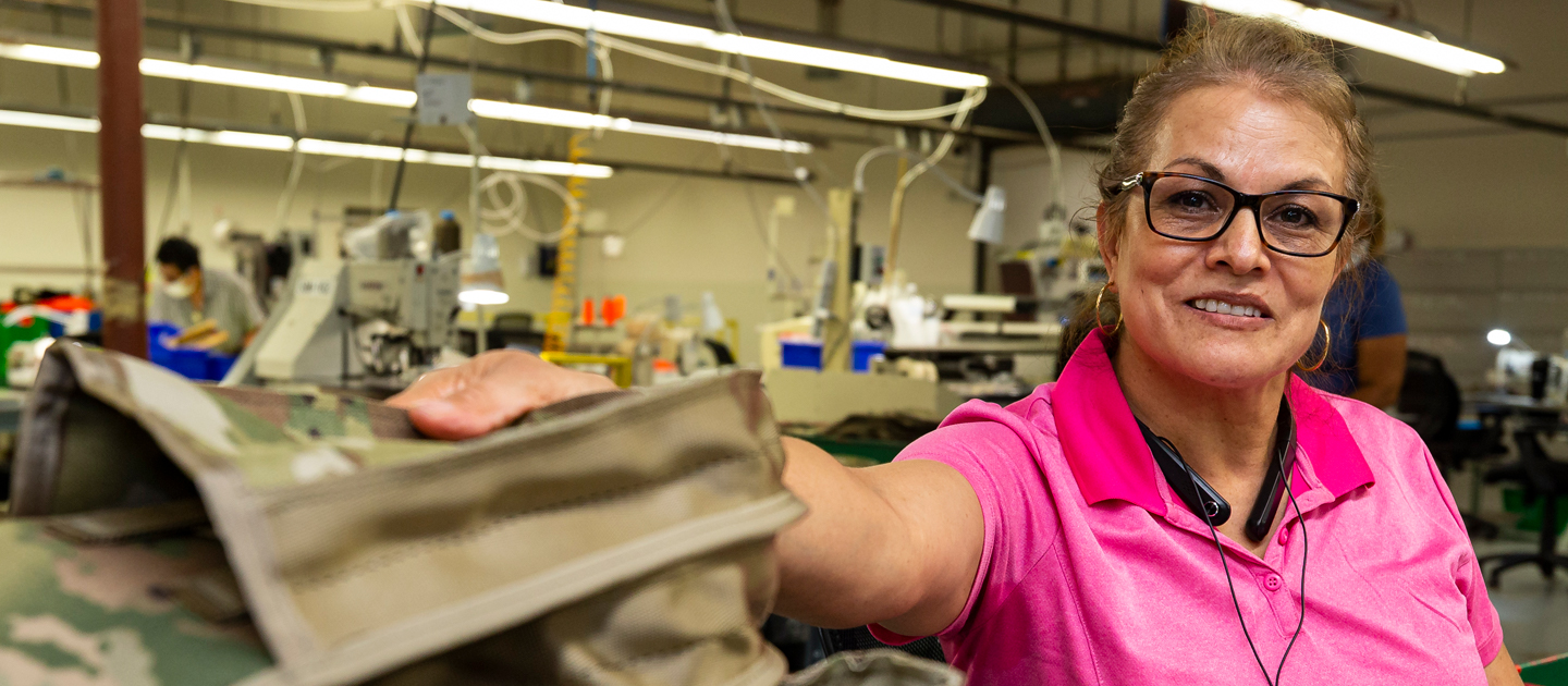 Woman who is visually impaired smiles at the camera as she works at her industry job at Envision Dallas.