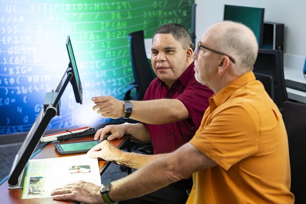 two men working on computer monitor using assistive technology