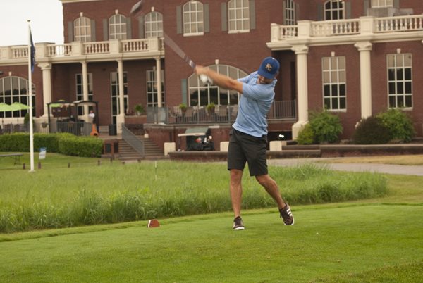 Golfer swings at ball with Terradyne Country Club in background