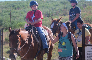 Boy campers learn to ride horses with their camp guides.