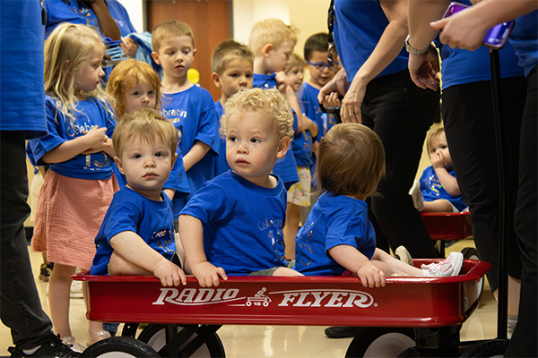 15 years of Impact: From No doors to Opening New Ones Children at ECDC sitting in a wagon at the annual graduation celebration.