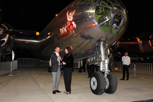 Two people standing in front a large b-29 doc airplane at the Evening with Envision gala 2022