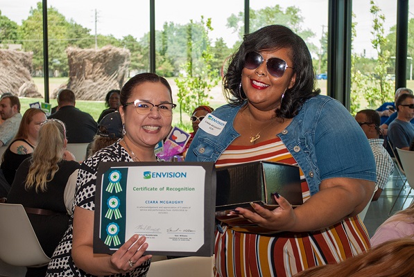 Envision NIB Employees of the Year Honored at Luncheon Wichita luncheon with Monica and Ciara holding up awards with a crowd in the background