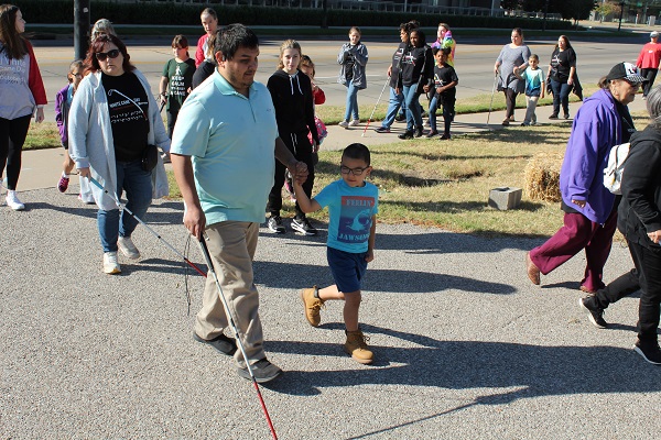 Envision Employee Jose Leal, his son, employee Terese Goren, and others enjoy the walk on a sidewalk