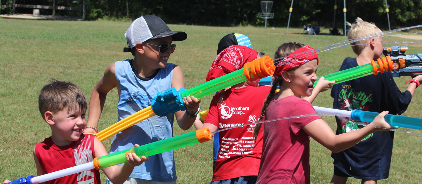 Children at Heathers Camp enjoying the summer heat with water gun play.