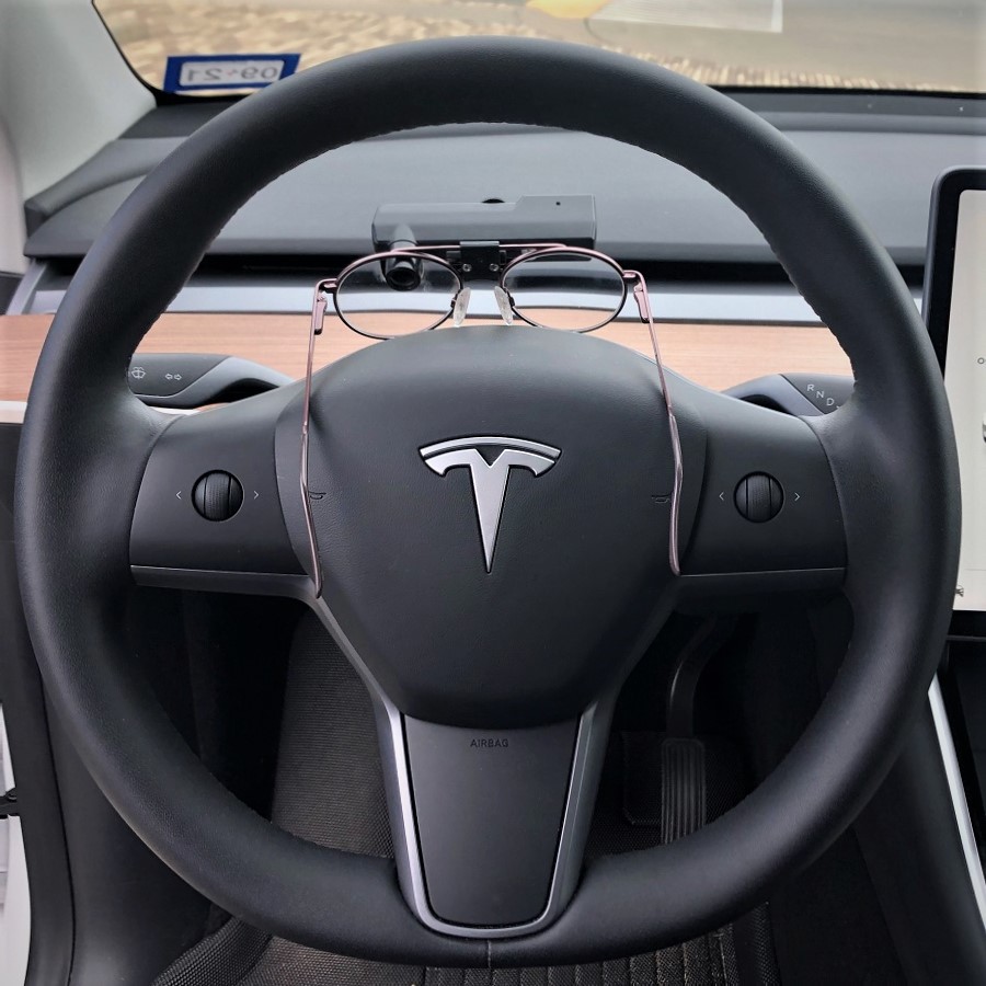 Tesla steering wheel with glasses sitting on top of it