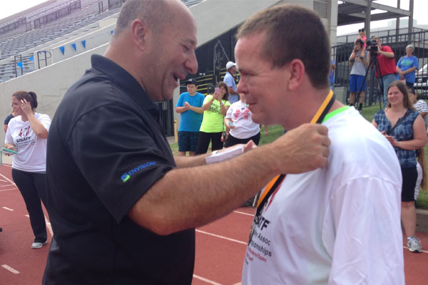 Michael Monteferrante places a medal on Kelly, an Envision employee, at a track meet.