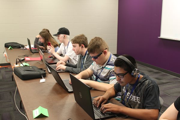 Group of blind or low vision students sitting at a table with laptops learning about technology