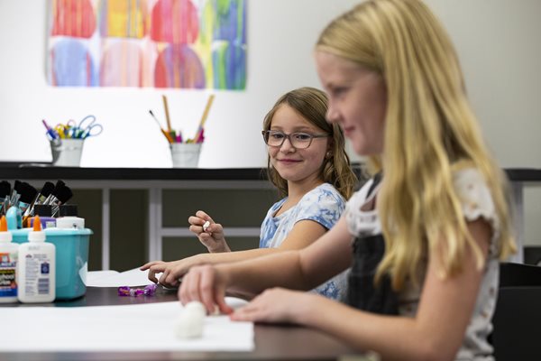 Two children enjoy creating art in arts studio