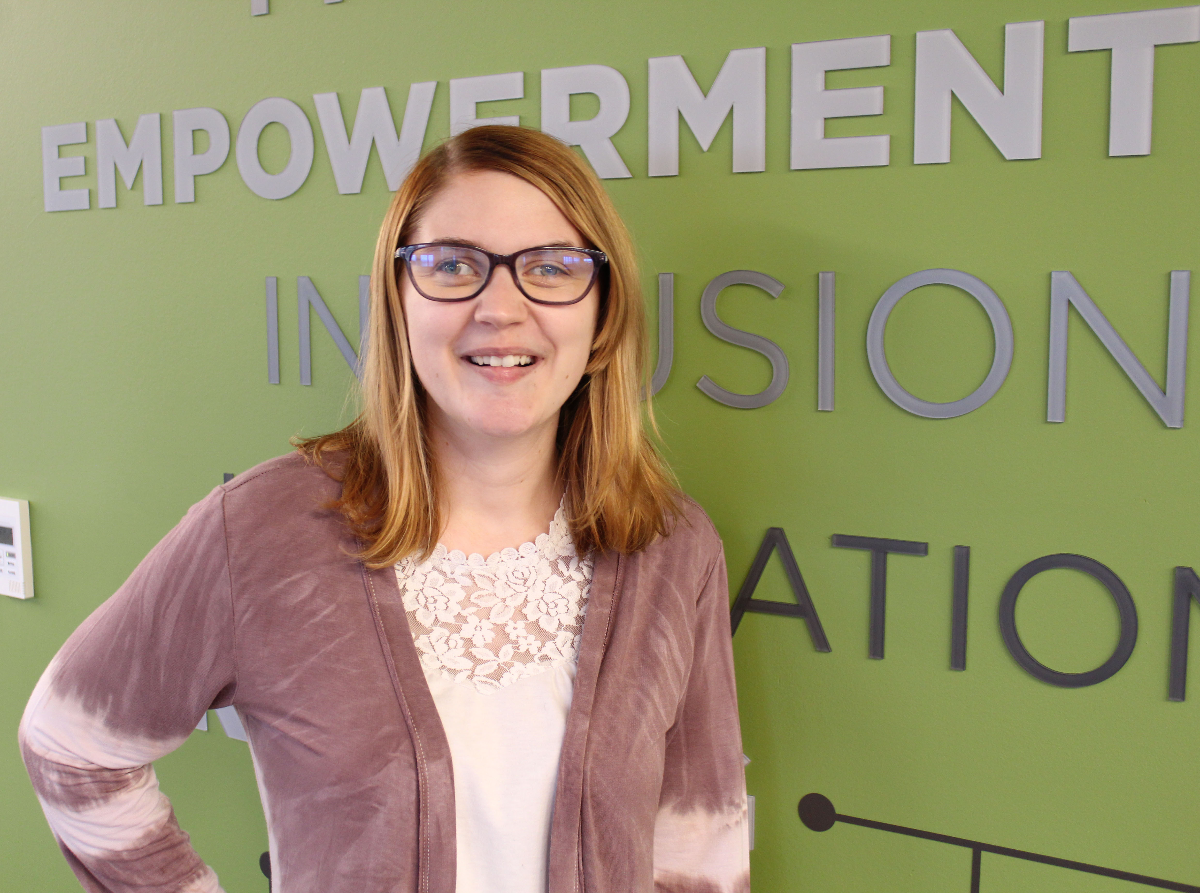 Headshot of Alison smiling at the camera and standing in front of a green wall at Envision's Workforce Innovation Center