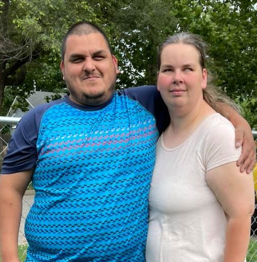 Jose and his wife standing next to each with Jose's arm around his wife, Ember
