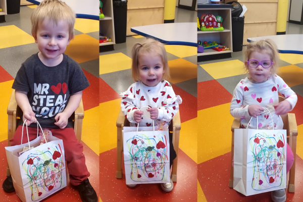 Three children holding their valentines day bags.