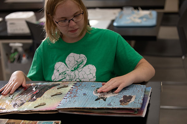 Artist who is visually impaired feels the texture of the book she created.