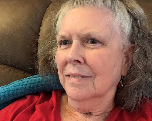 Headshot of Becky Smith in a red shirt smiling on her couch