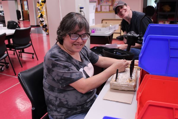 Annette Willoughby with Robby Sweetland in the background prepare pen cartridges for assembly.