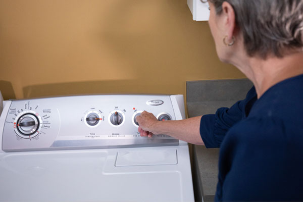 Woman who is losing her vision learns how to use a washing machine with accessible aids.
