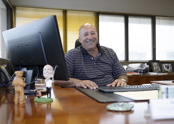 Michael sitting at his desk at Envision smiling for the camera