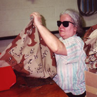 Woman, who is blind, works on camouflage material for a product sold at the Base Service Centers.