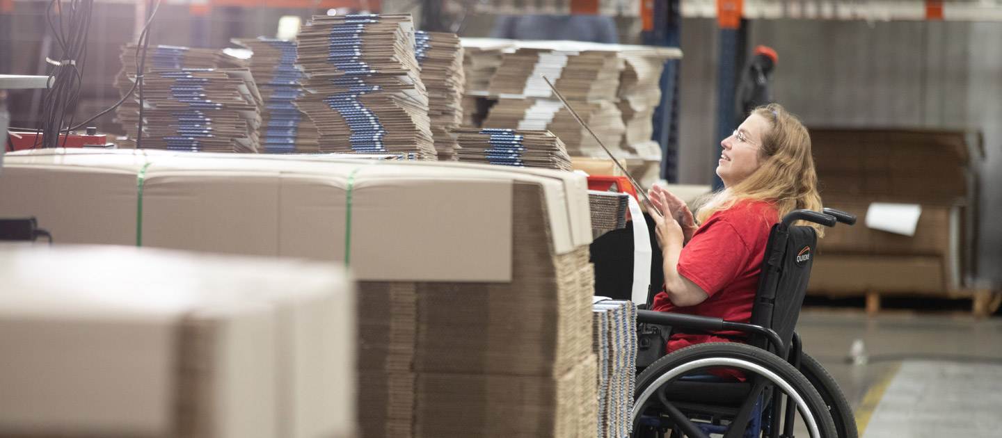 Woman in a wheelchair places labels on boxes at Envision Industries.