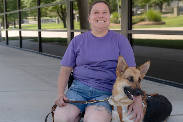 Woman who is blind sits with her guide dog outside of Envision.