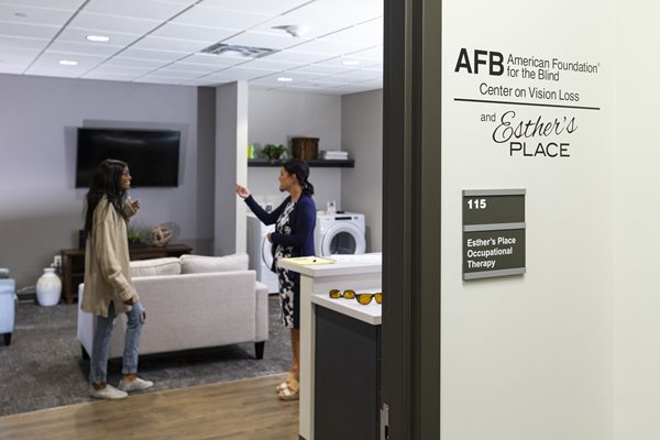 Two women in Envision Dallas's Esther Place model apartment talking about low vision occupational therapy solutions for the home