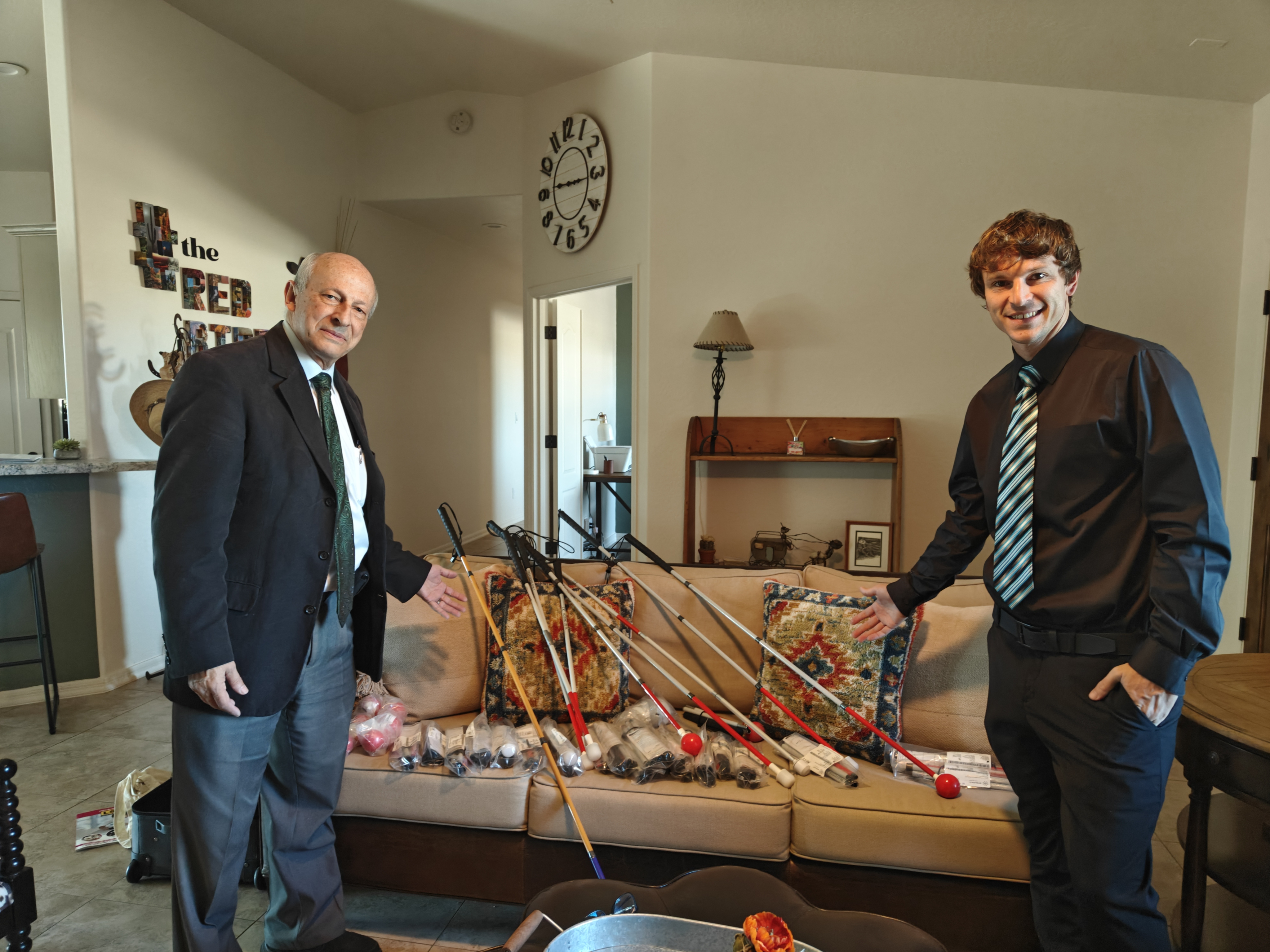 Dr. Fletcher and Taylor Fletcher smiling as a variety of white canes are spread out on a table.