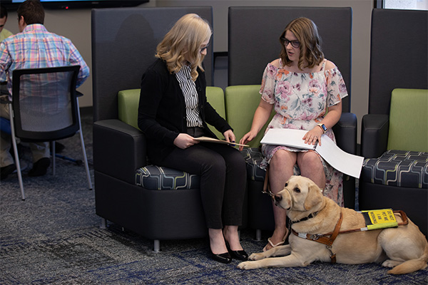 Professional Envision employee stands outside the office with her guide dog.