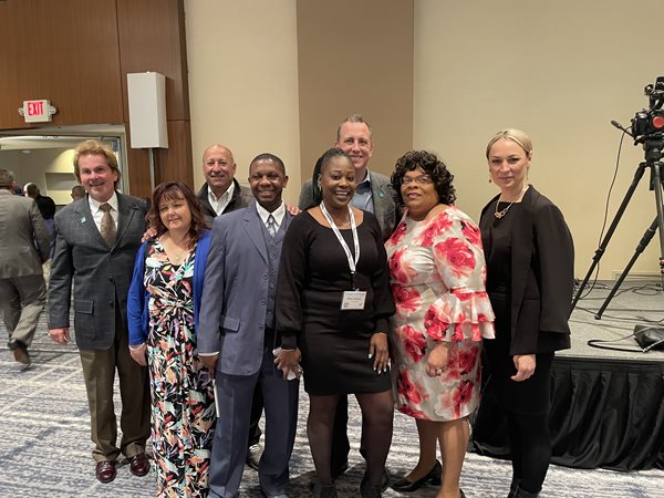 A group of people posing together in front of a stage at a conference. 