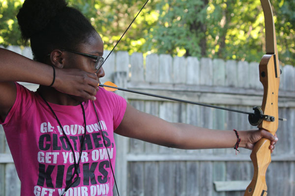 Girl who is visually impaired shoots an arrow at  Heathers Camp.