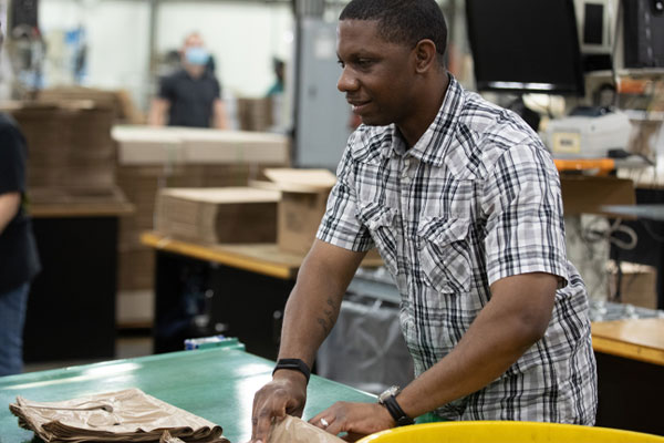 Sedrick prepares can liners to be packed in Envision boxes.