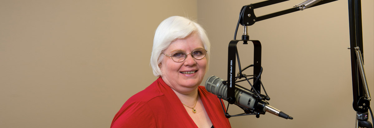 Envision employee Regina Henderson smiling in front of a microphone in a recording studio