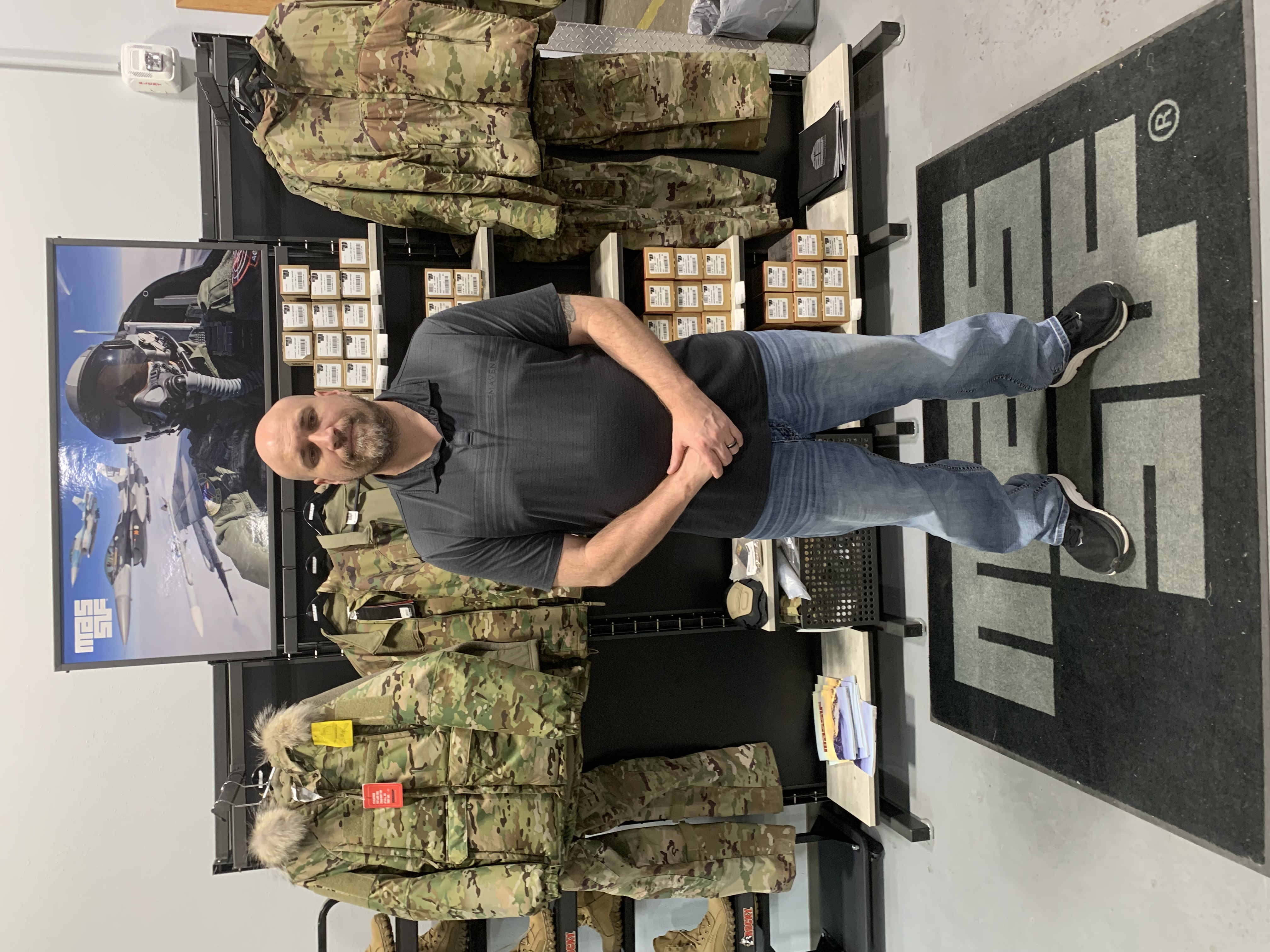 Will Quist, Envision Base Supply Store Purchasing and Contracts Manager, stands in front of shelves