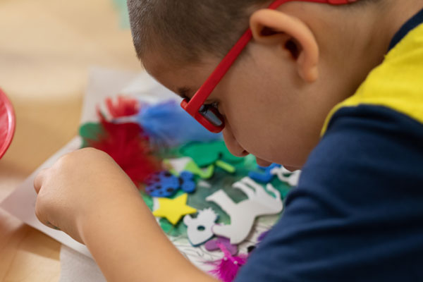 Young boy who is visually impaired works on a collage in the Envision Arts studio.