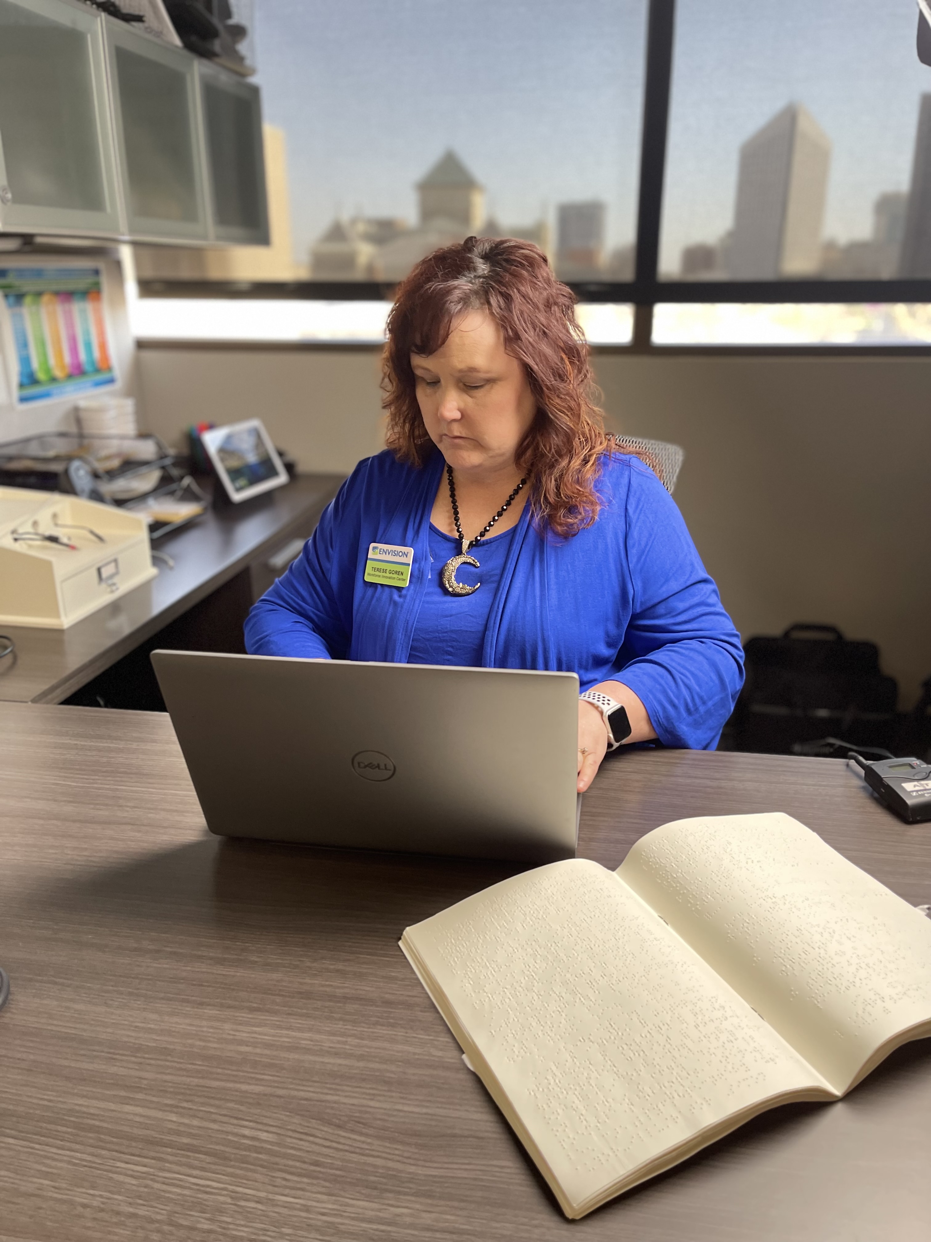 Terese at her desk reviewing accessibility on her laptop.