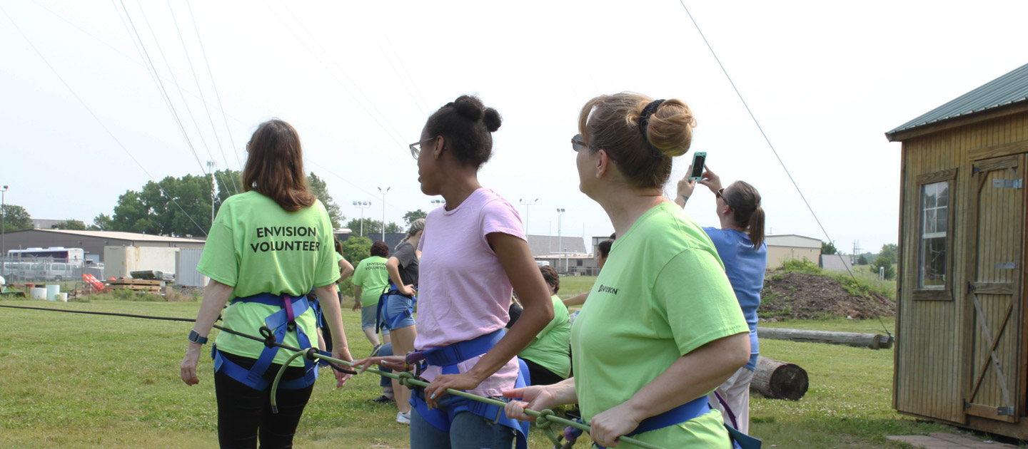 Volunteers hold onto a cable for the zip line at Level Up activity.