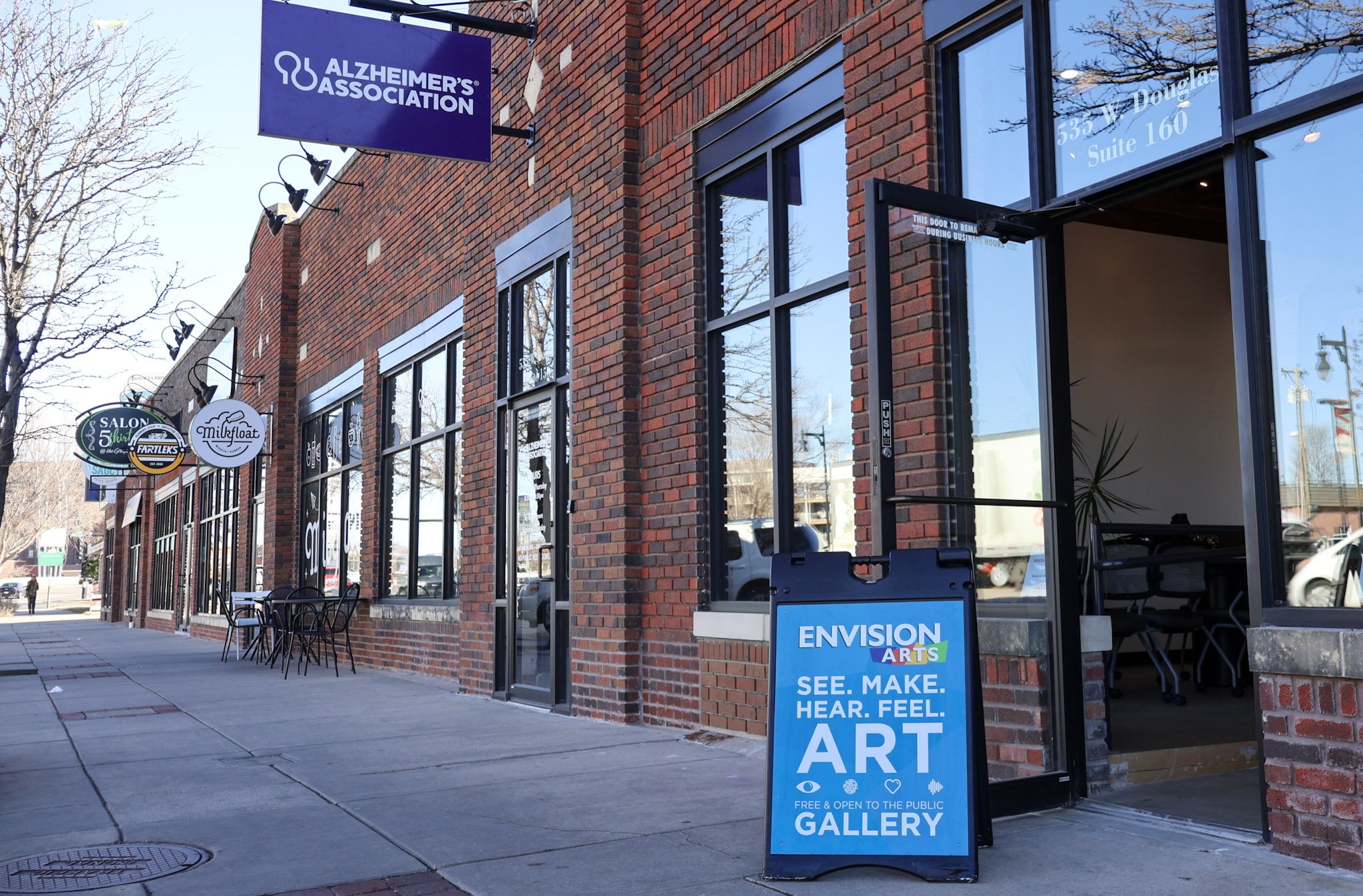The front of the new arts building with a welcoming art sign propping the door open. 